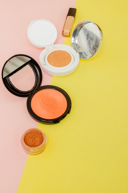 Make up products spilling on to a bright yellow and pink background with copy space, minimal style