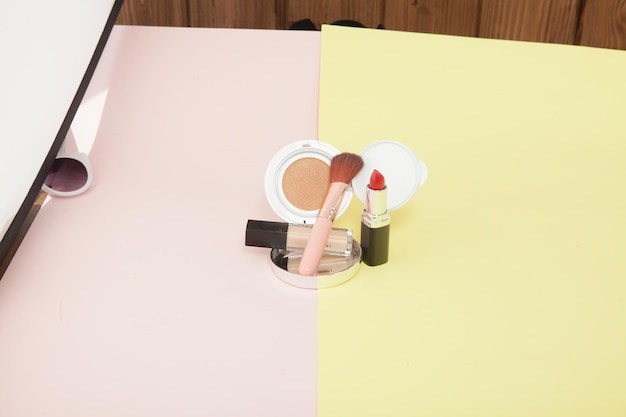 Make up products spilling on to a bright yellow and pink background with copy space