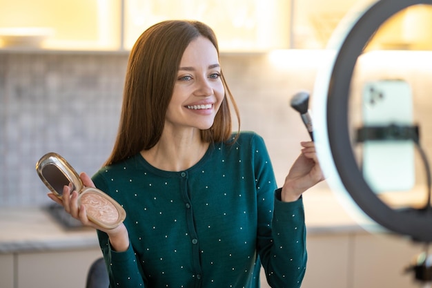 Make up. Woman holding face brush and doing make up