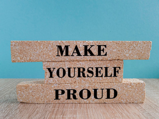 Make yourself proud Words on a brick blocks on beautiful wooden table blue background