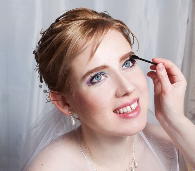 Photo makeup artist applies mascara to the bride s eyelashes. close-up portrait