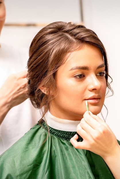 Makeup artist and hairdresser prepare the bride making hairstyle and makeup in a beauty salon