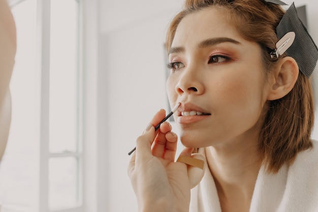 Makeup artist is applying lipstick to the clients