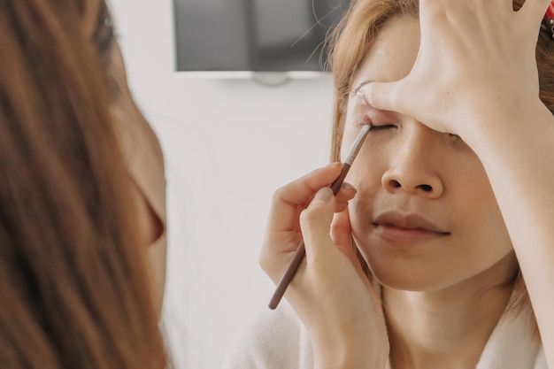 Makeup artist is applying makeup on client eyes