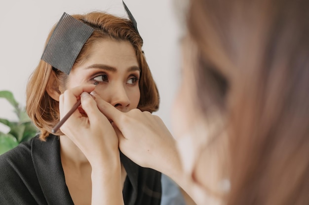 Makeup artist is applying makeup on client eyes