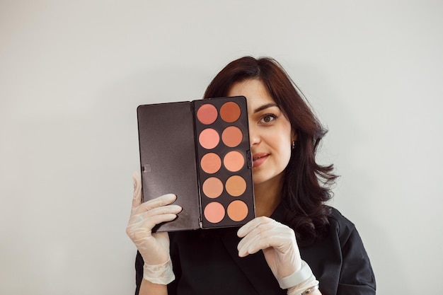 Makeup artist showing eyeshadow palette nude colors palette white background