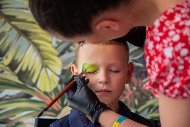 Makeup artist at the workplace to apply face painting to the model Makeup artist at halloween party draw face painting on child's face