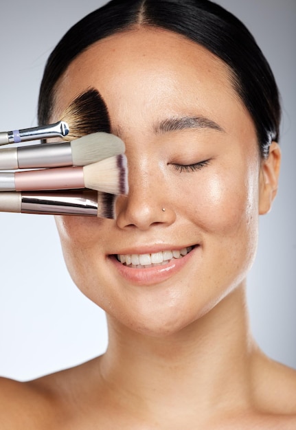 Makeup beauty and Asian woman with brushes in studio for cosmetics design Creative cosmetology and happy girl with different makeup brushes on natural face for fashion style and beauty products