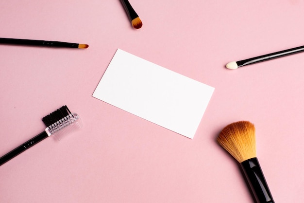 Makeup brush and white business card on pink background A horizontal template for a makeup artist39s business card or flyer design with copy space