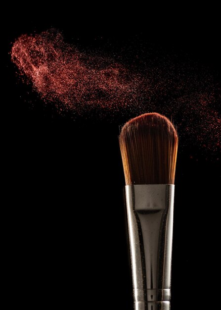 Makeup brushes and powder on a black background