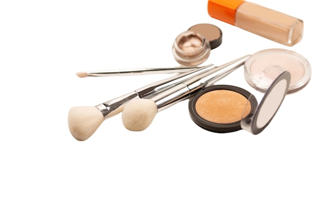 Makeup brushes, powder and liquid foundation over a white background, isolated