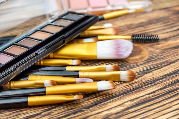 Makeup brushes with eyeshadow on wooden table Close up