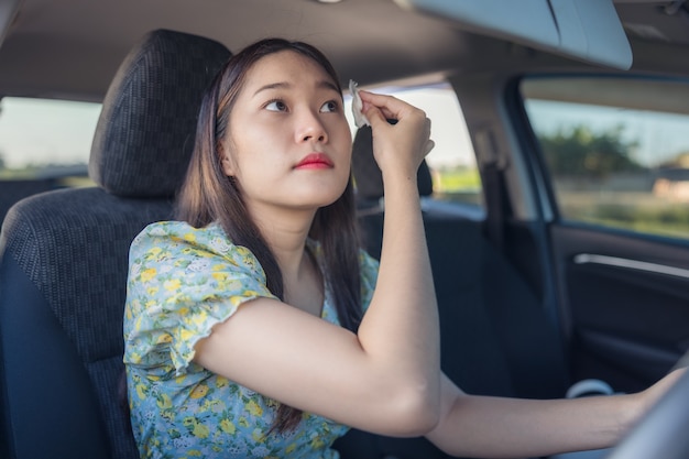 Makeup in the car, young woman applying makeup while driving