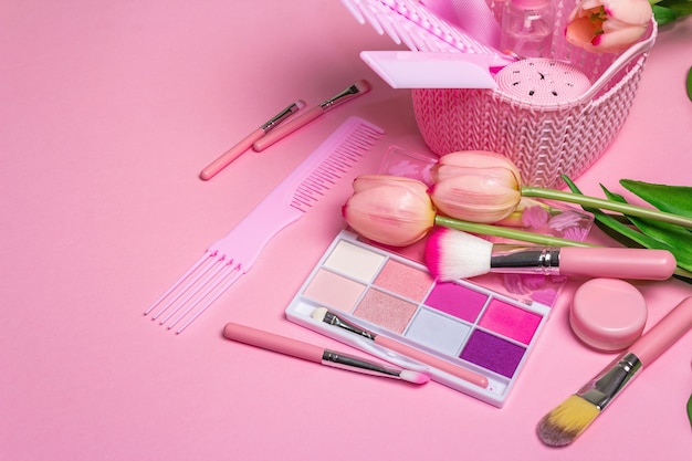 Makeup cosmetic set and hair combs on pink.