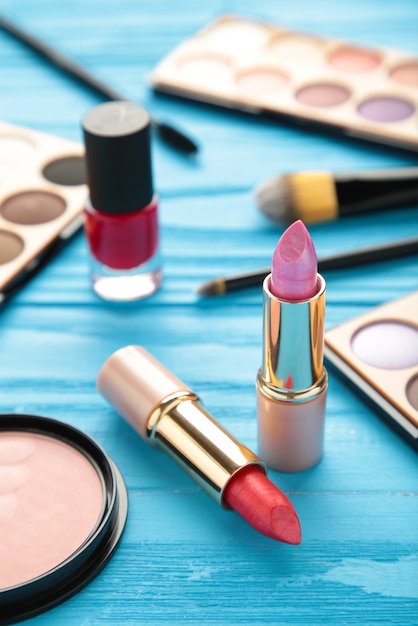 Makeup lipstick and cosmetics on blue background. Flat lay, top view. Beauty and fashion concept. Vertical photo