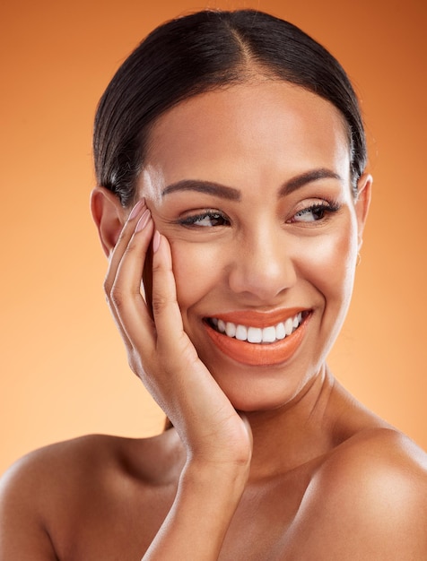 Makeup skincare and woman with smile for cosmetics against an orange studio background Thinking happy and young model with happiness for luxury beauty dermatology and health of body and skin