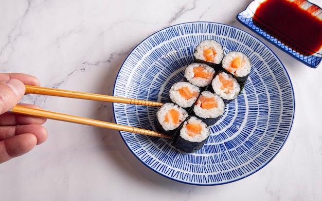 Maki rolls with salmon The man39s hand holds a roll with chopsticks