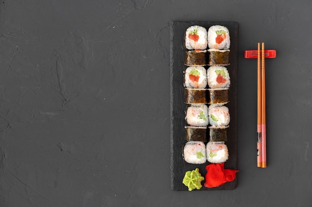 Maki sushi roll on black stone plate top view