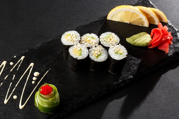 Maki Sushi Rolls with cucumber or avocado on black stone on dark 