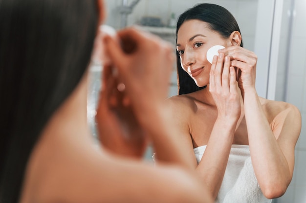 Making care of her skin Young caucasian woman with slim body shape is indoors at daytime