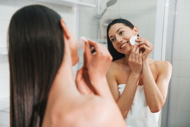 Making care of her skin Young caucasian woman with slim body shape is indoors at daytime