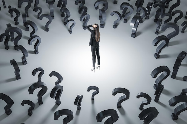 Making decision and finding solution concept with pensive businesswoman on light floor surrounded by black question marks