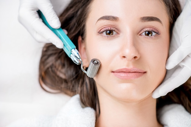 Making dry needlying procedure on woman's face in the cosmetology office