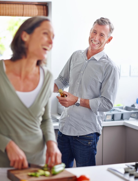 Making each other laugh Shot of a mature couple laughing while preparing a meal together in the kitchen