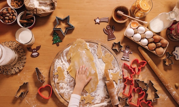 Making gingerbread at home little girl cutting cookies of gingerbread dough christmas and new year