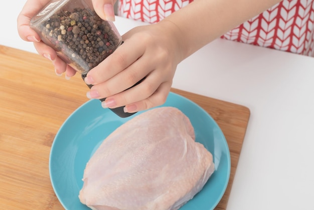 Making a healthy diet broth Female hands add spices to raw chicken breast