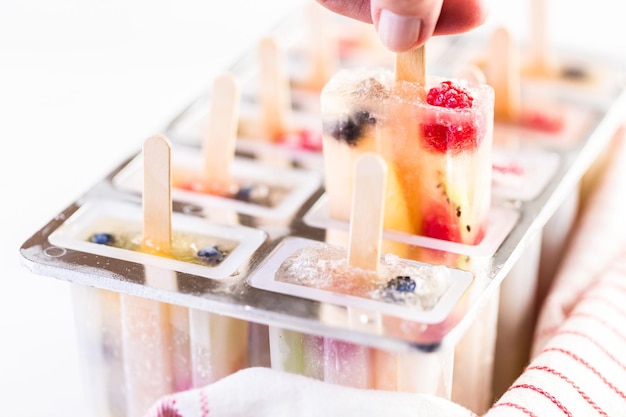 Photo making homemade fresh fruit popsicles with apple juice in frozn ice pop maker.