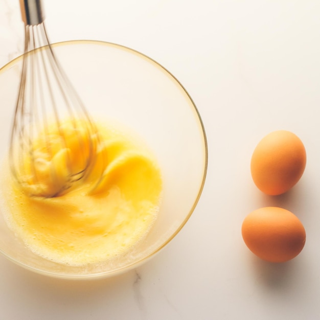 Making of mixing eggs in bowl on marble table as homemade food flat lay top view food brand photography flatlay and recipe for cooking blog menu or cookbook design