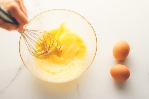 Making of mixing eggs in bowl on marble table as homemade food flat lay top view food brand photography flatlay and recipe for cooking blog menu or cookbook design