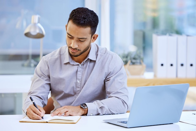 Making notes is what helps me to stay on top of things Shot of a businessman making notes while sitting at his desk