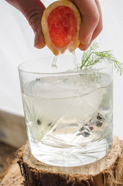 Making a Pink grapefruit and rosemary gin cocktail served in prepared glass on a tropical beach bar Drink concept