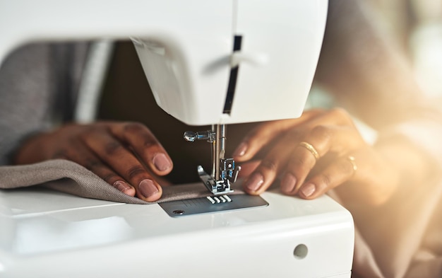 Making raw material into something beautiful Cropped shot of a young fashion designer using a sewing machine in her workshop