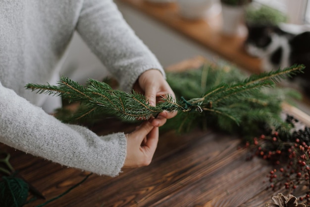 Making rustic christmas wreath seasonal advent Female hands holding fir branches on wooden table