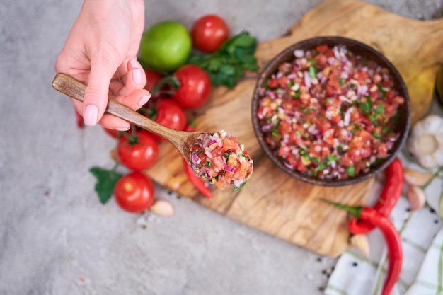 Making salsa dip sauce woman mixing chopped ingredients in wooden bowl