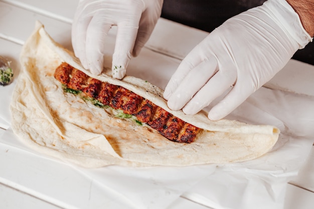 Making shawarma with kebab meat and arabic bread.