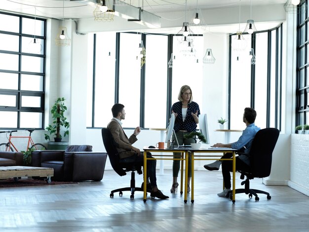 Making sure theyre on the right track Full length shot of a businesswoman addressing two male coworkers at their desk in the office