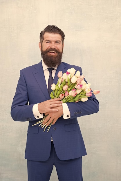 Making surprise Gentleman with tulips Spring is coming Greetings Bearded man with tulip bouquet Love date Womens day March 8 Spring gift Bearded man hipster with flowers Celebrate spring