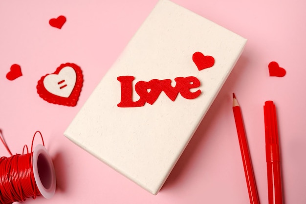 Making Valentine's Day gift box on pink background. Valentine diy hobby. Making heart decoration, Handmade concept