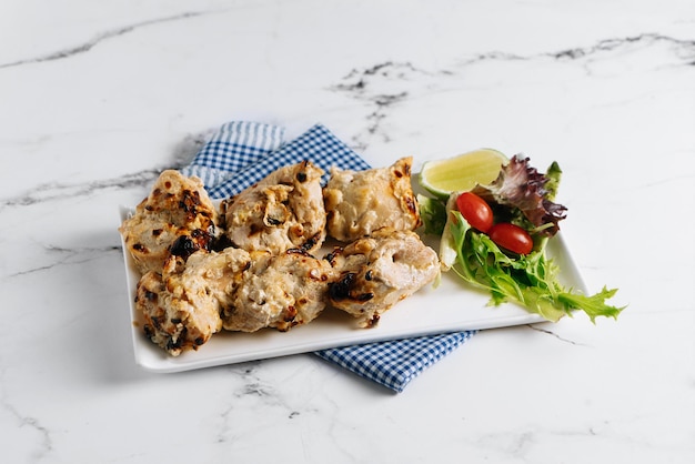 Malai Chicken Kebab bbq with lime in a dish isolated on napkin side view on grey background