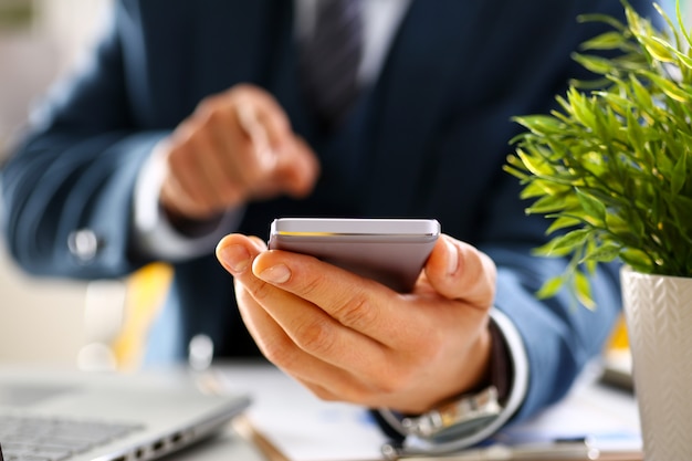 Male arm in suit hold phone