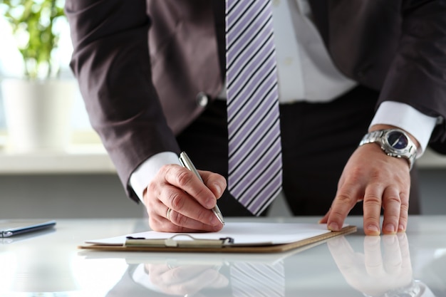 Male arm in suit and tie fill form clipped to pad