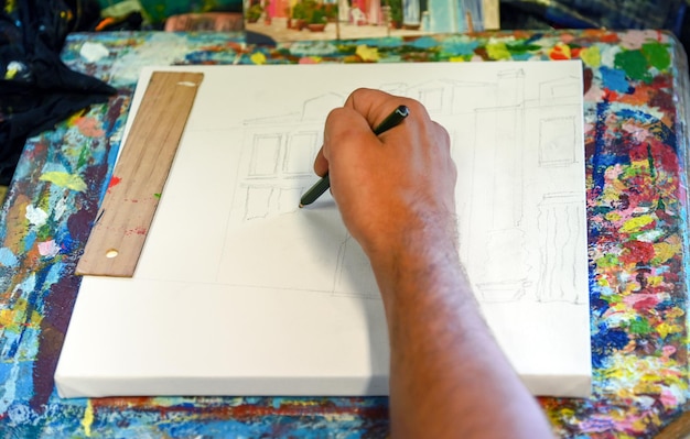 Male artist drawing house on canvas