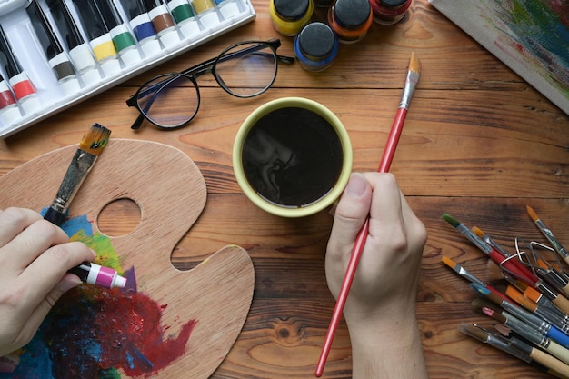 Male artist holding painting brush and mixing color on palette