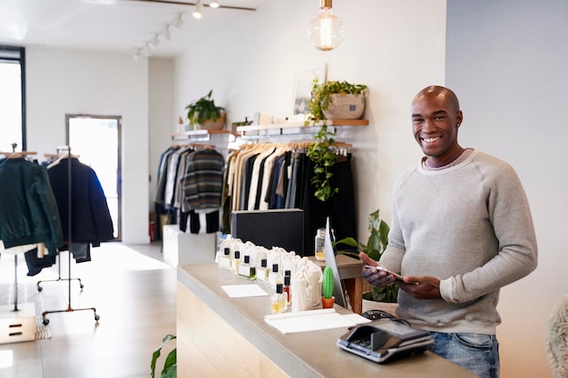 Photo male assistant smiling behind the counter in clothing store