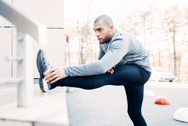 Male athlete doing stretching exercise before run. Jogger on morning fitness workout. Runner in sportswear on training outdoor