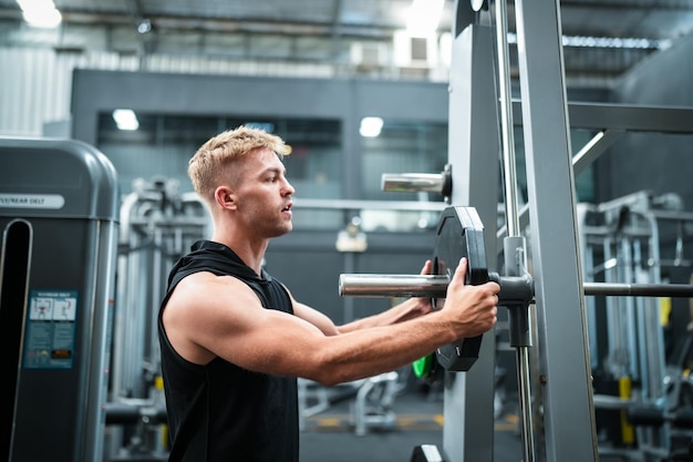 Male athlete exercising in the gym lifting weights pulling joints